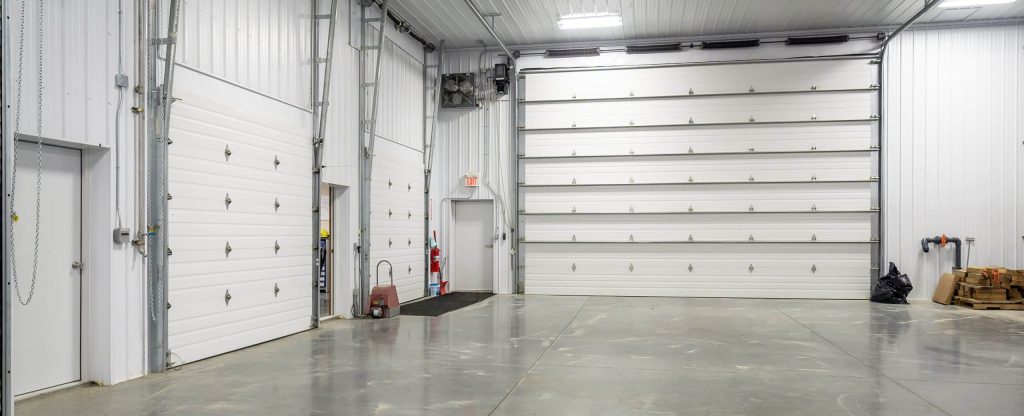 A bright white post-frame commercial building with 10 overhead doors