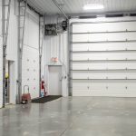 A bright white post-frame commercial building with 10 overhead doors