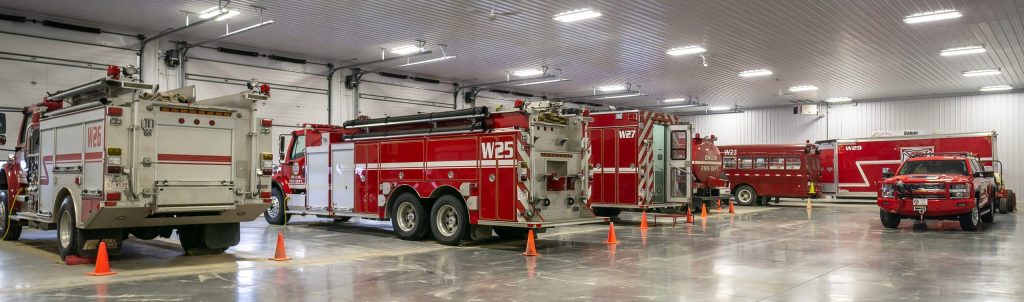 A bright white post-frame commercial building with 10 overhead doors