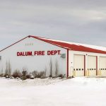 A bright white post-frame commercial building with 10 overhead doors
