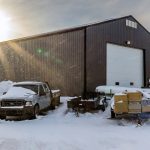 A charcoal post-frame commercial shop with an overhead door