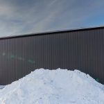 A charcoal post-frame commercial shop with an overhead door