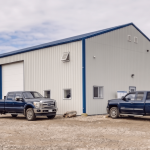 A bone white post-frame commercial shop with heron blue exterior trims