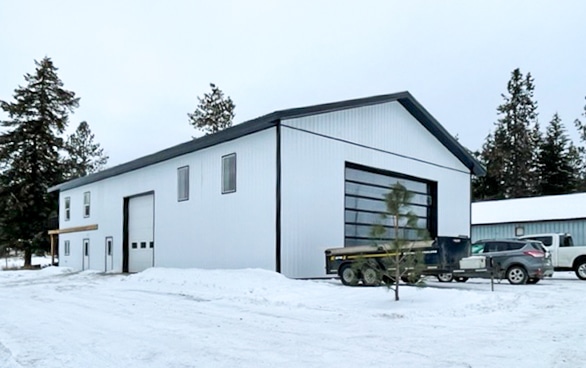 A bright white post-frame Residential Shouse with soffits and an overhead door