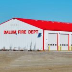 A bright white post-frame commercial building with 10 overhead doors
