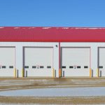 A bright white post-frame commercial building with 10 overhead doors