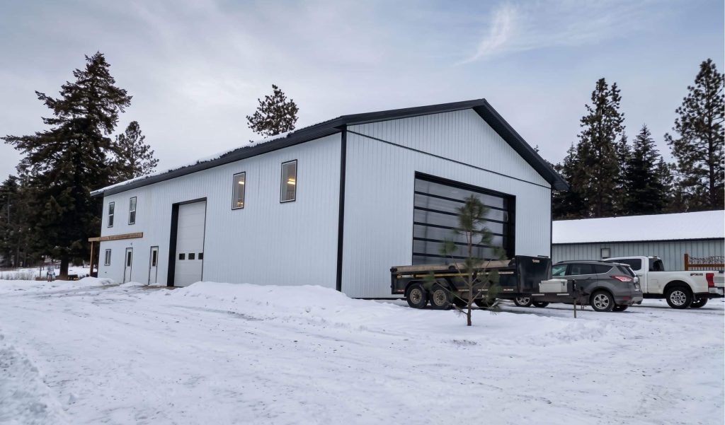 A bright white post-frame Residential Shouse with soffits and an overhead door