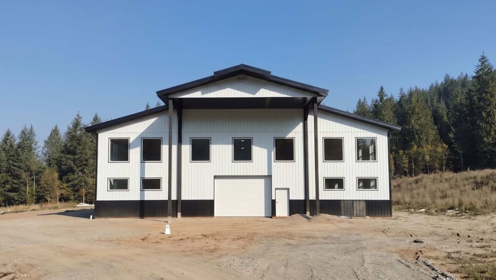 A bright white post-frame equestrian riding arena with black wainscoting