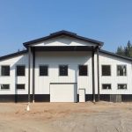 A bright white post-frame equestrian riding arena with black wainscoting