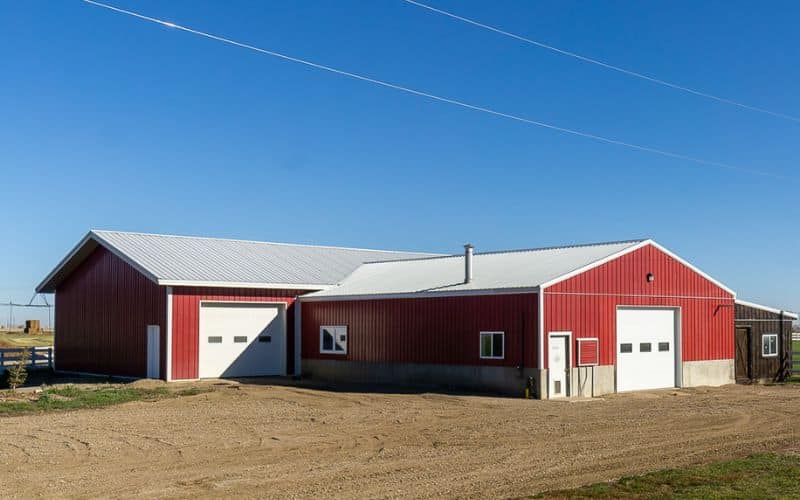 A dark red post-frame equestrian Shop with four overhead and four bi-fold doors