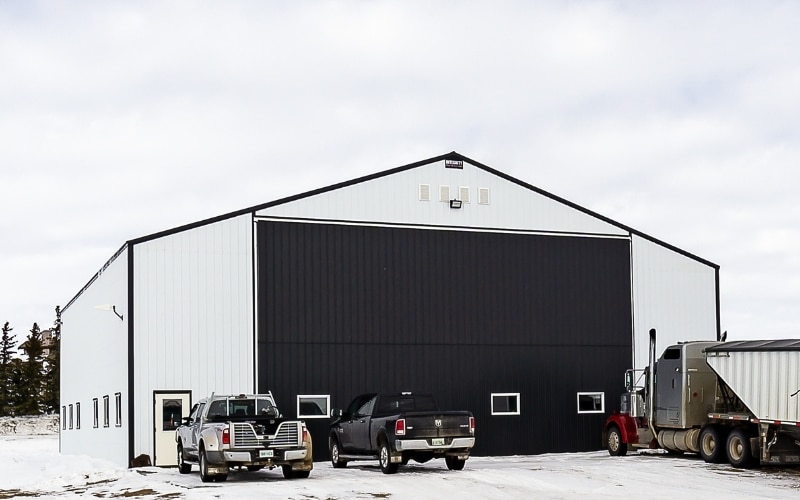 A bright white post-frame machine shed with a bi-fold door