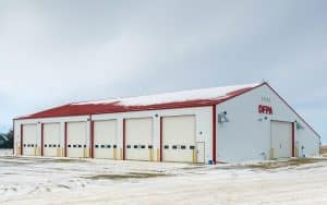 A bright white post-frame commercial building with 10 overhead doors