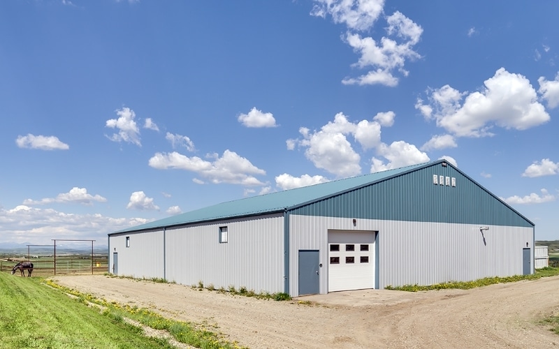 A post-frame equestrian barn with overhead doors and white walls