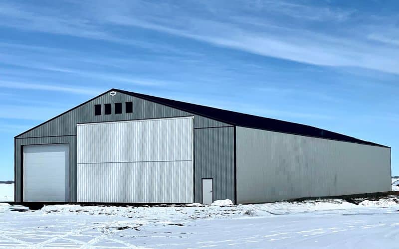 A regent grey post-frame agriculture Machine Shed with overhead and bi-fold doors