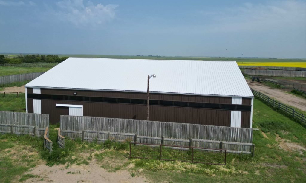 A coffee brown post-frame livestock shelter with overhead and sliding doors