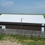 A coffee brown post-frame livestock shelter with overhead and sliding doors
