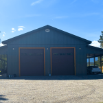 A dark sage post-frame shop with open lean-tos, soffits, and wooden trims