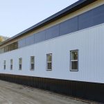 A bright white post-frame equestrian riding arena with black wainscoting