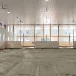 A bright white post-frame equestrian riding arena with black wainscoting