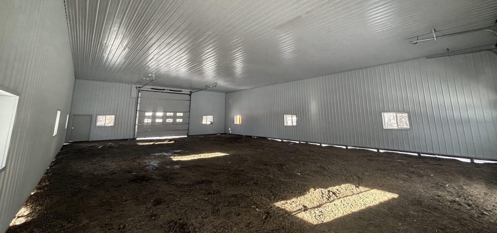 A charcoal post-frame lifestyle and agricultural shop with open lean-to porch, and an overhead door