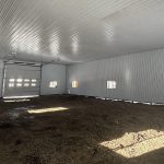 A charcoal post-frame lifestyle and agricultural shop with open lean-to porch, and an overhead door