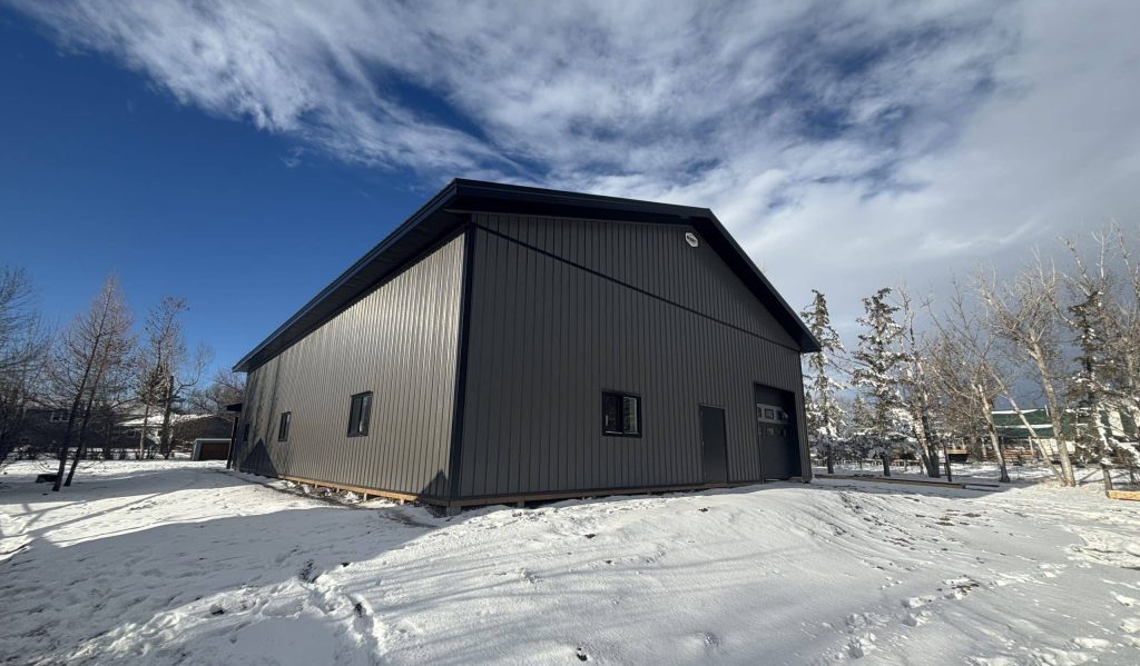 A charcoal post-frame lifestyle and agricultural shop with open lean-to porch, and an overhead door