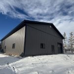 A charcoal post-frame lifestyle and agricultural shop with open lean-to porch, and an overhead door