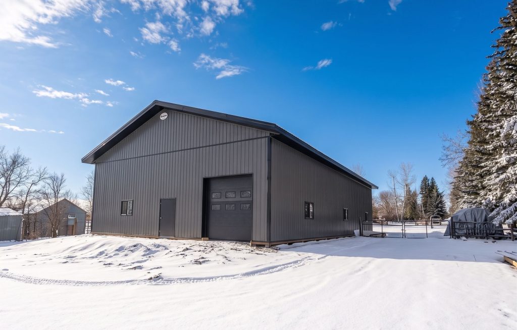 A charcoal post-frame lifestyle and agricultural shop with open lean-to porch, and an overhead door