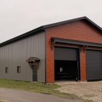 A post-frame commercial storage building with premium Frontier metal cladding and black overhead doors