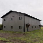 A post-frame commercial storage building with premium Frontier metal cladding and black overhead doors