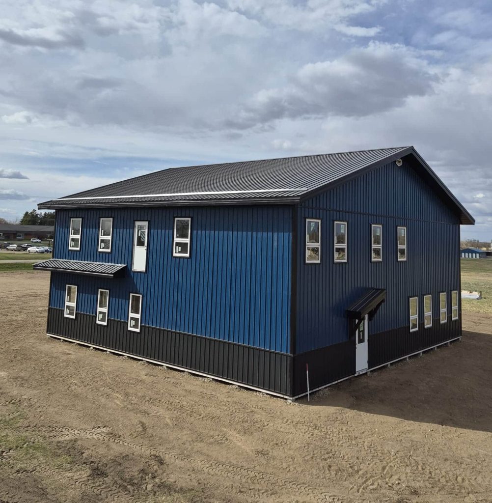 A heron blue post-frame commercial office with soffits, wainscoting, and a front porch