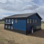 A heron blue post-frame commercial office with soffits, wainscoting, and a front porch