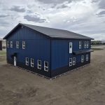 A heron blue post-frame commercial office with soffits, wainscoting, and a front porch