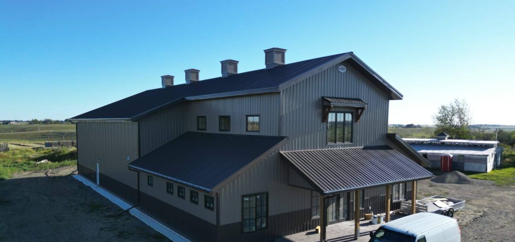 A post-frame residential barndominium with buckskin walls and coffee brown wainscoting