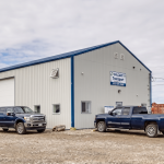 A bone white post-frame commercial shop with heron blue exterior trims