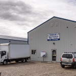 A bone white post-frame commercial shop with heron blue exterior trims