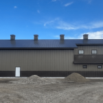 A post-frame residential barndominium with buckskin walls and coffee brown wainscoting