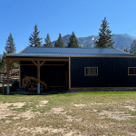A black post-frame shop with copper penny trims and an overhead door