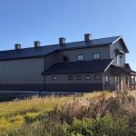 A post-frame residential barndominium with buckskin walls and coffee brown wainscoting