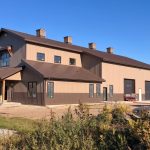 A post-frame residential barndominium with buckskin walls and coffee brown wainscoting