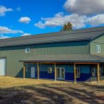 Post-frame residential building - The Shouse in greed metal cladding and a wrap-around porch in Saskatchewan