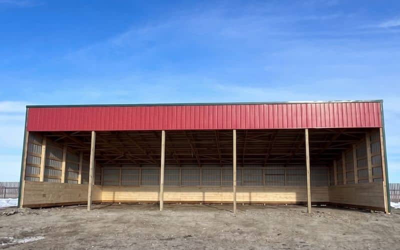 A bright red post-frame livestock shelter