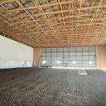 A bone white post-frame agricultural storage building with bi-fold door