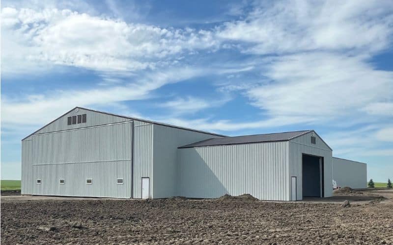 A bone white post-frame agricultural storage building with bi-fold door
