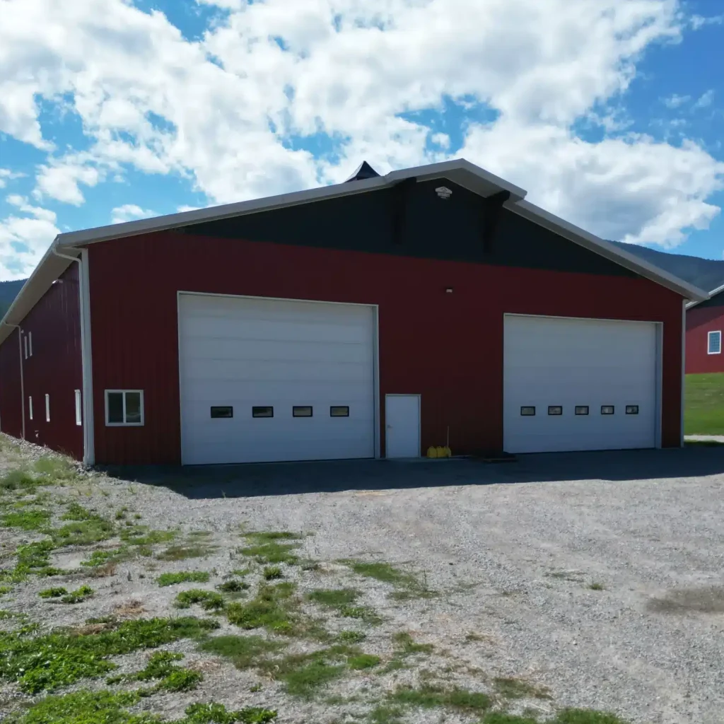 A dark red post-frame agriculture storage building with cupolas