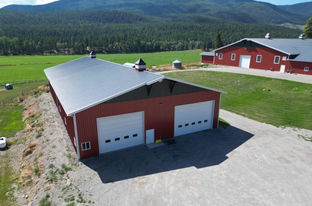 A dark red post-frame agriculture storage building with cupolas