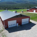A dark red post-frame agriculture storage building with cupolas