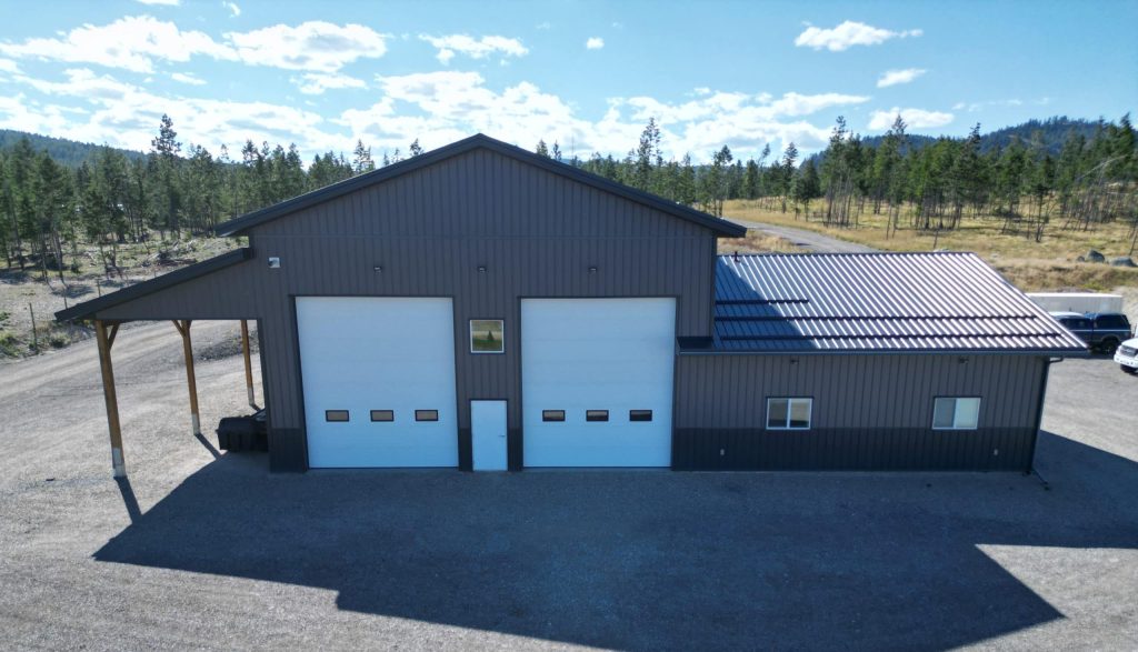 A charcoal post-frame agriculture storage building with wainscoting and overhead doors