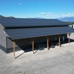 A charcoal post-frame agriculture storage building with wainscoting and overhead doors