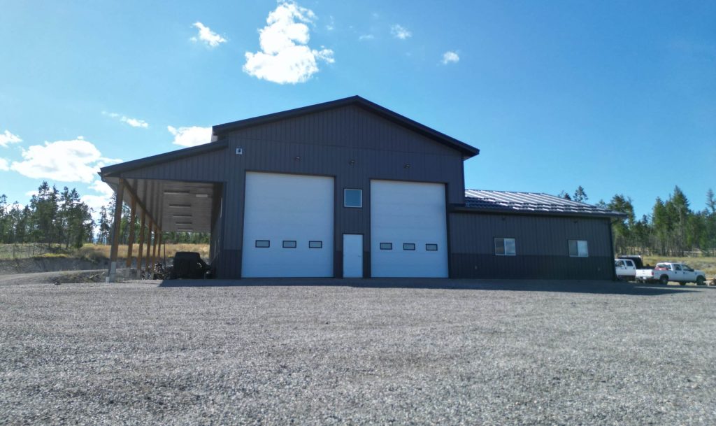 A charcoal post-frame agriculture storage building with wainscoting and overhead doors